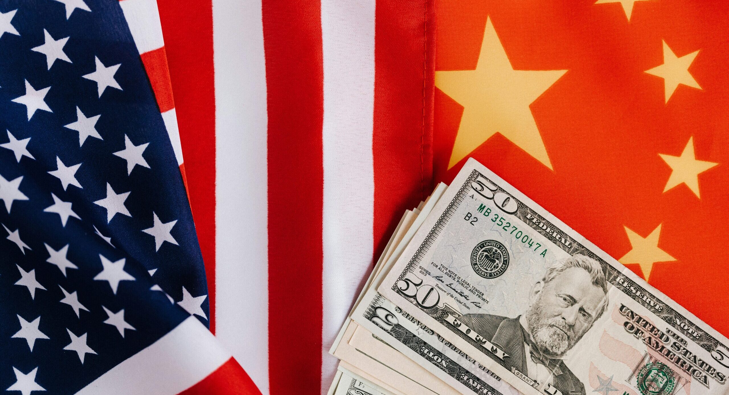 Conflicto comercial China-EE.UU. representado con las banderas de ambos países y billetes de dólar, símbolo del impacto económico y financiero global.